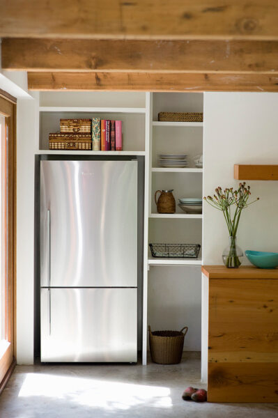 Moderner Edelstahlkühlschrank in Wandnische neben offenen Küchenregalen